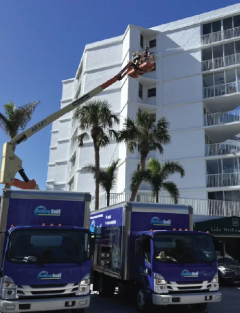 Company trucks and lift cleaning a multi-story facade
