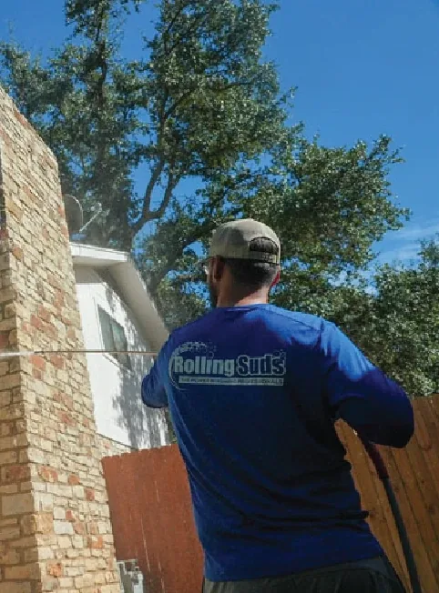 Technician washing a stone home exterior