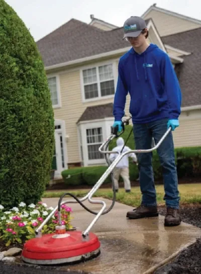 Technician cleaning a walkway with a surface cleaner